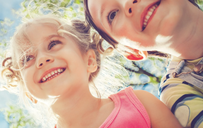 Two children happy and smiling demonstrating how good it feels to be in tune with their emotions through somatic awareness.